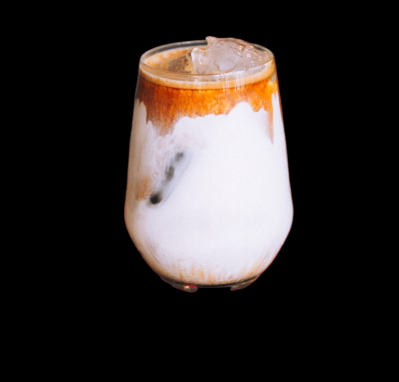 Glass of layered iced coffee with a black background